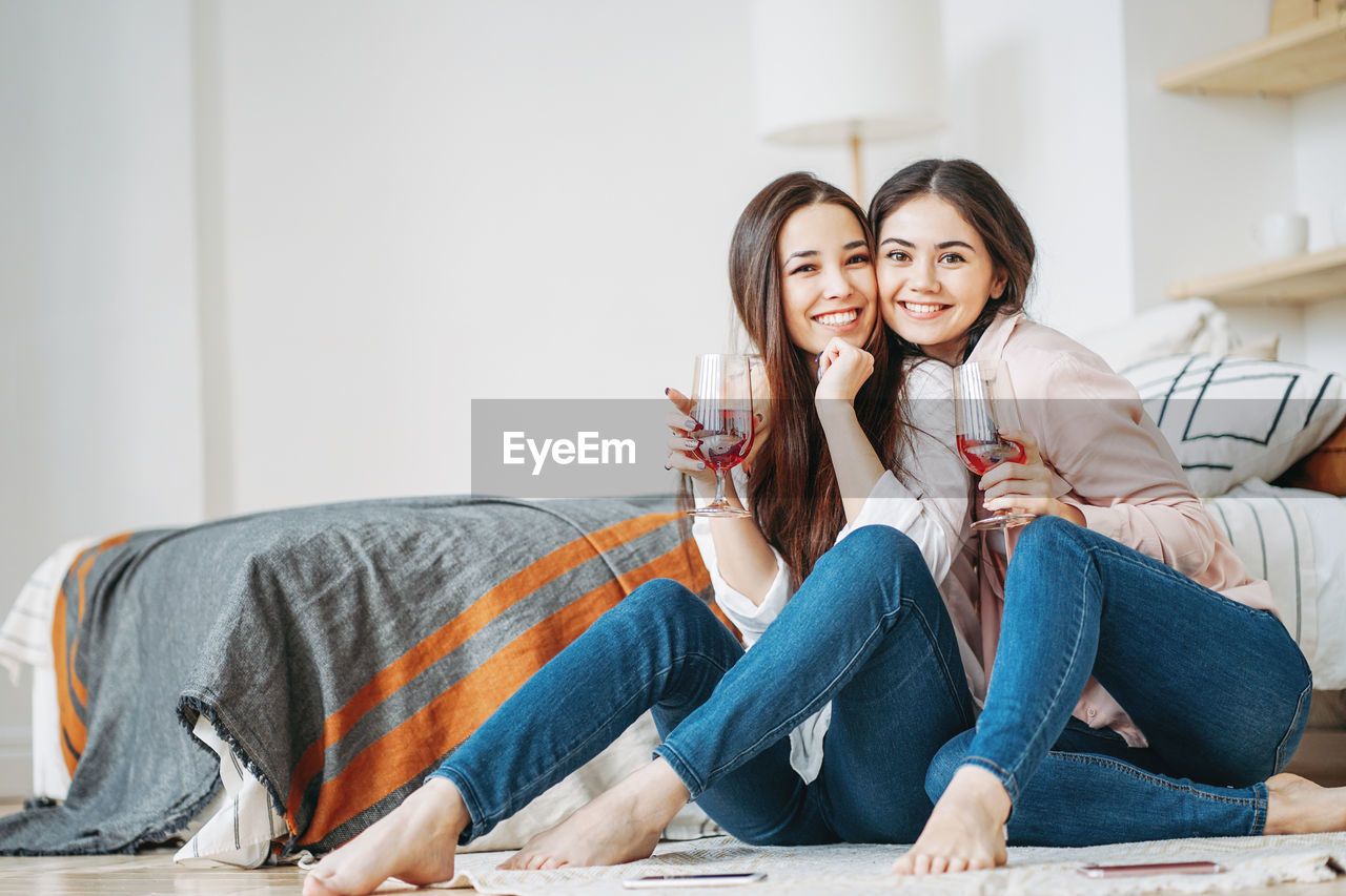 Portrait of happy friends enjoying wine at home