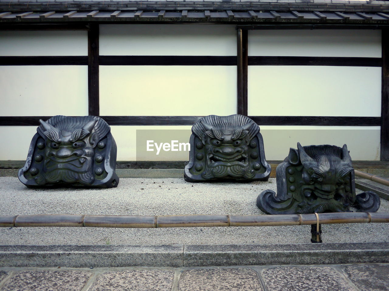 Group of three decorative roof tiles with faces of demons in a japanese garden