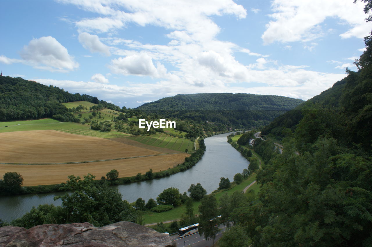 River amidst green mountains against cloudy sky