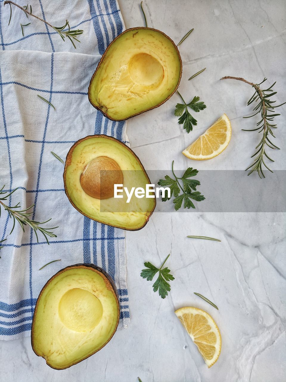 Fresh avocado with herbs and lemons lies on the table on white background. flat lay. top view.