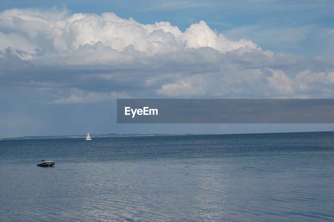 Boat sailing in sea against cloudy sky