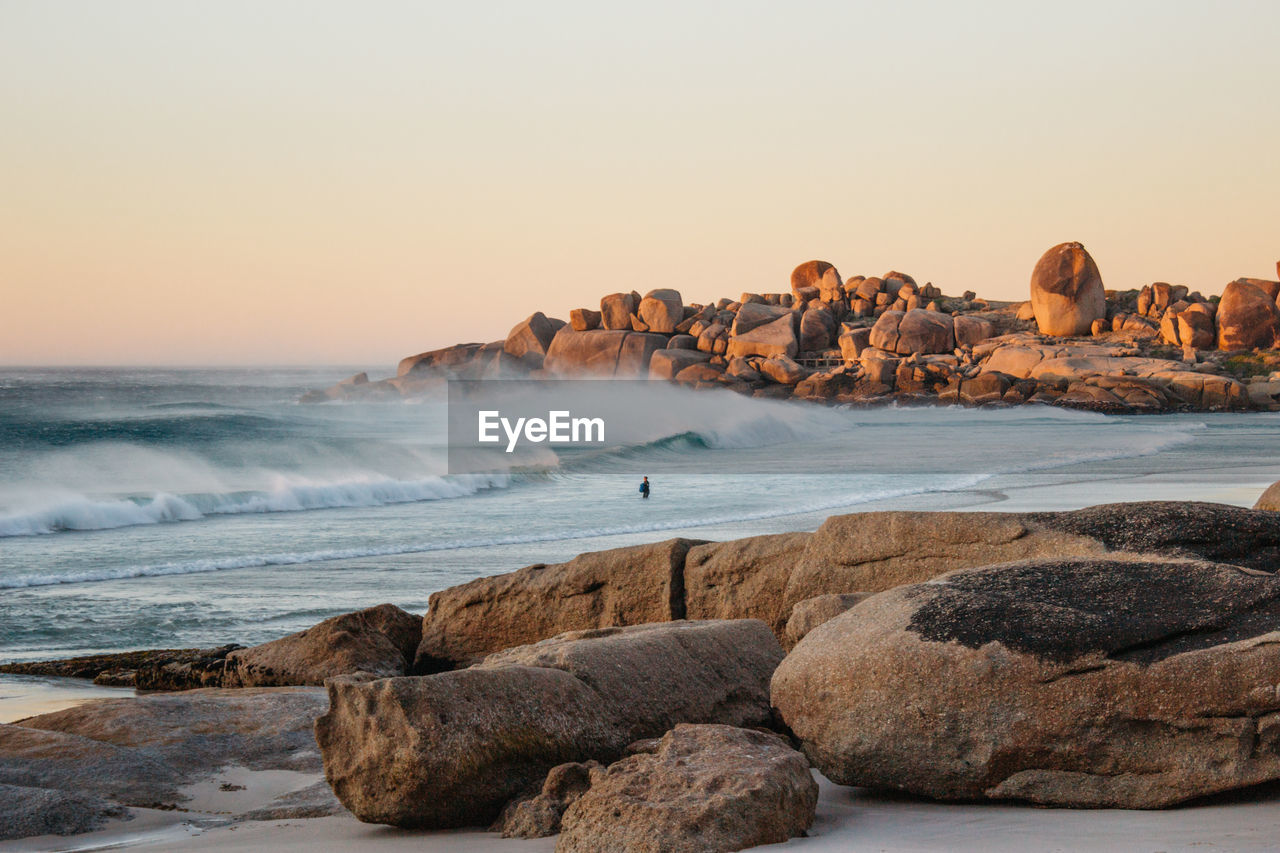 Scenic view of rocks on beach against clear sky