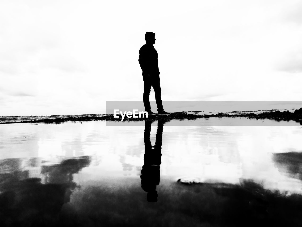 REAR VIEW OF SILHOUETTE MAN STANDING AGAINST SEA