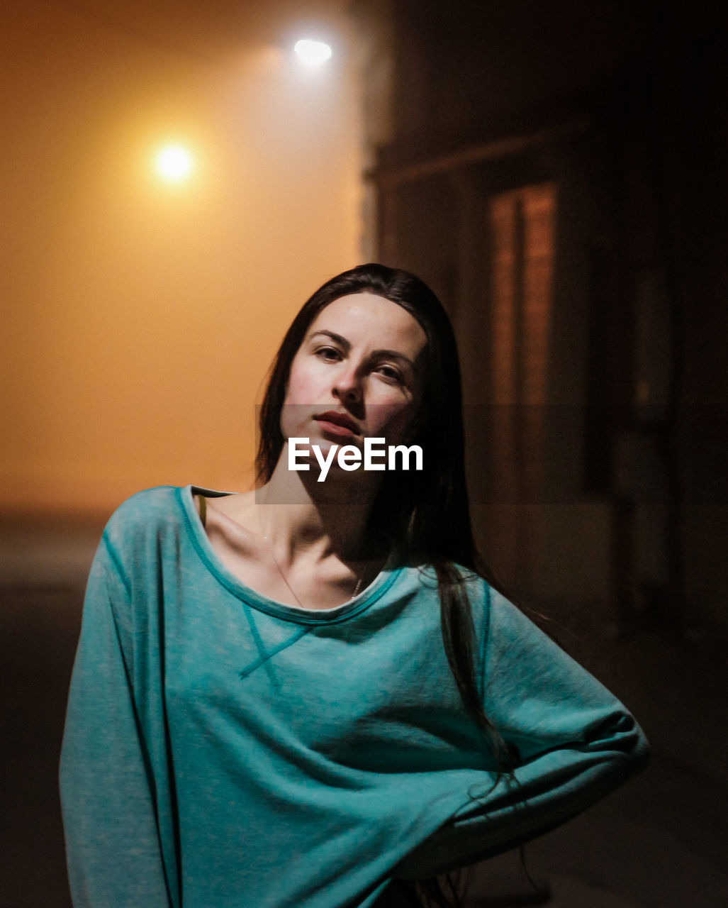 Portrait of young woman standing on road in city at night