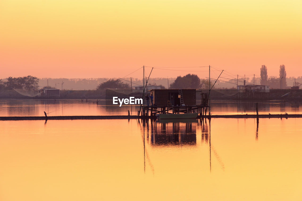 SCENIC VIEW OF LAKE AGAINST SKY AT SUNSET