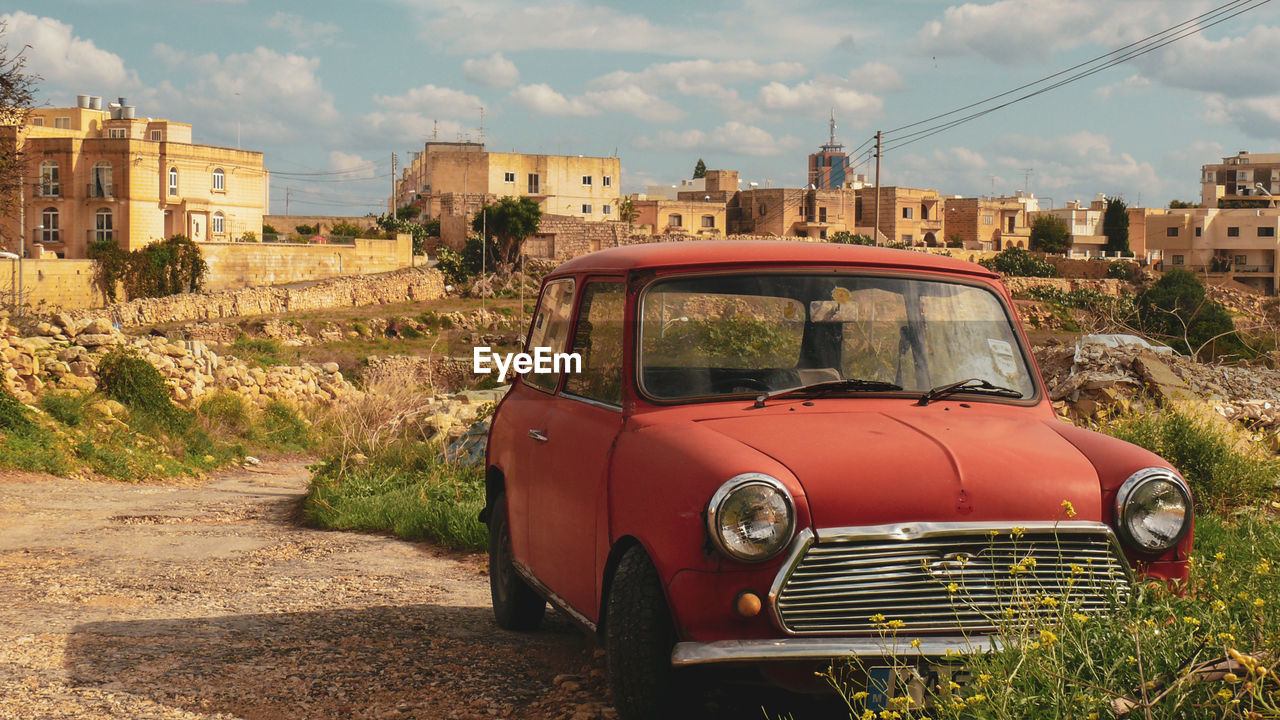 ABANDONED CAR ON LAND AGAINST SKY