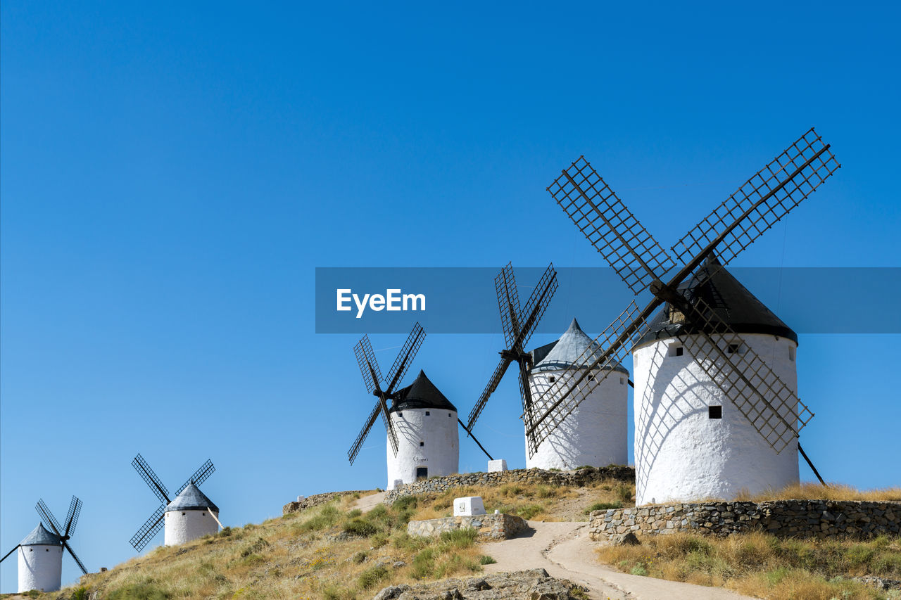 Traditional windmills on land against clear blue sky