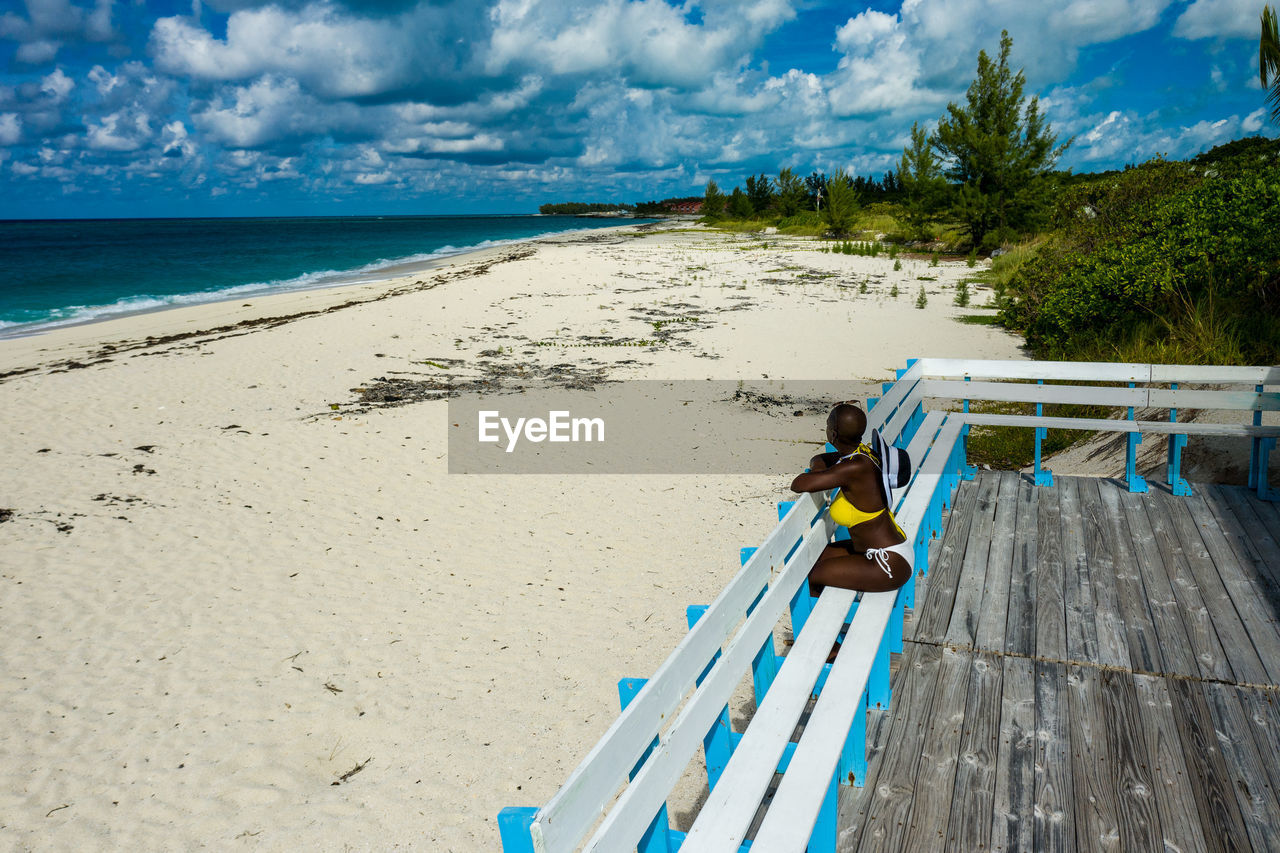 High angle view of woman sitting on bench at beach