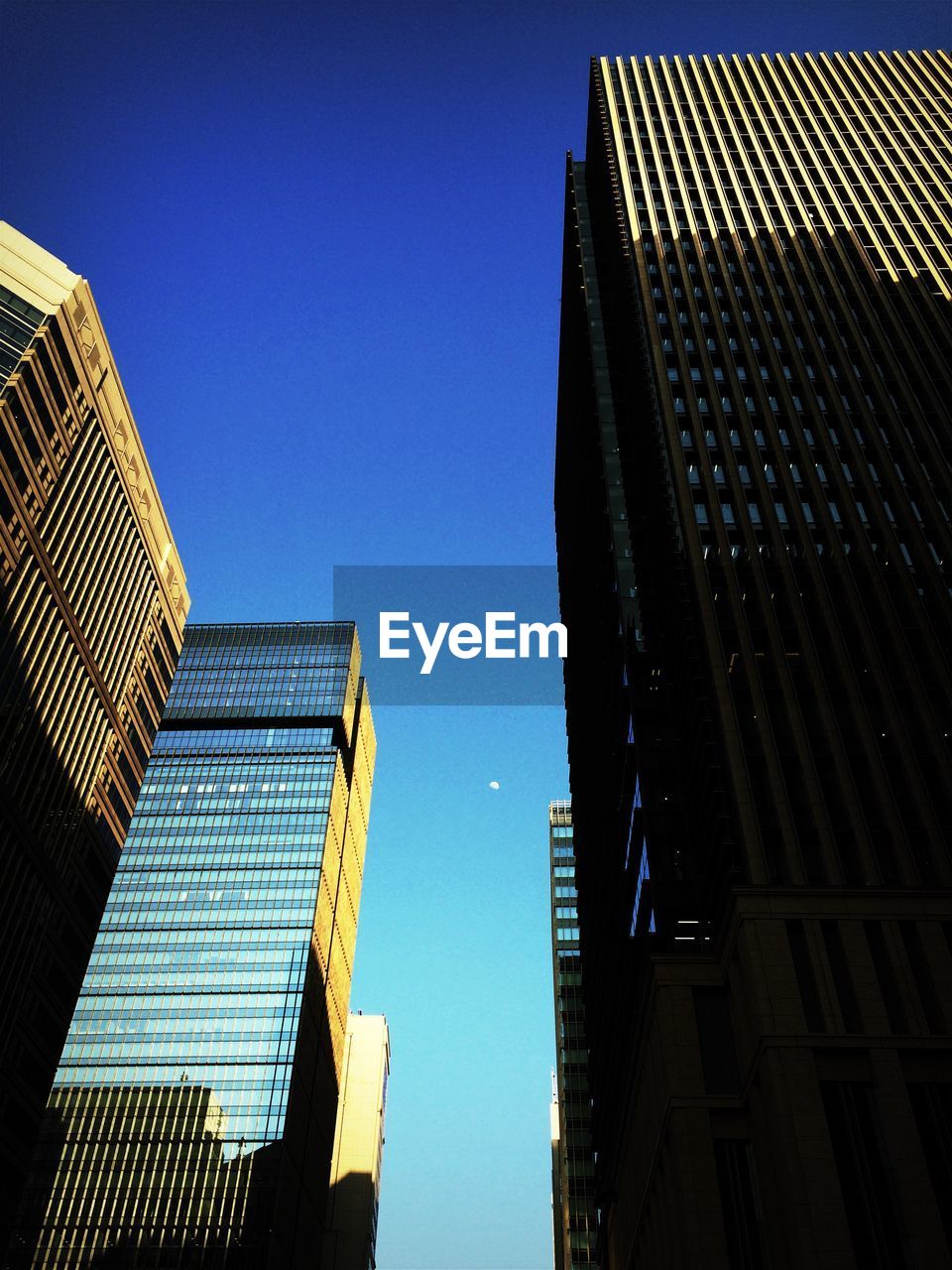 LOW ANGLE VIEW OF OFFICE BUILDINGS AGAINST BLUE SKY