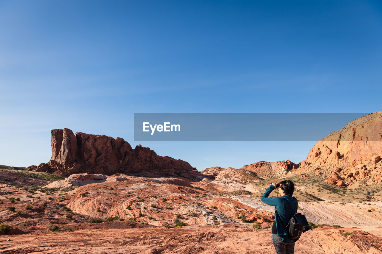 Woman looking with binoculars out into the desert landscape