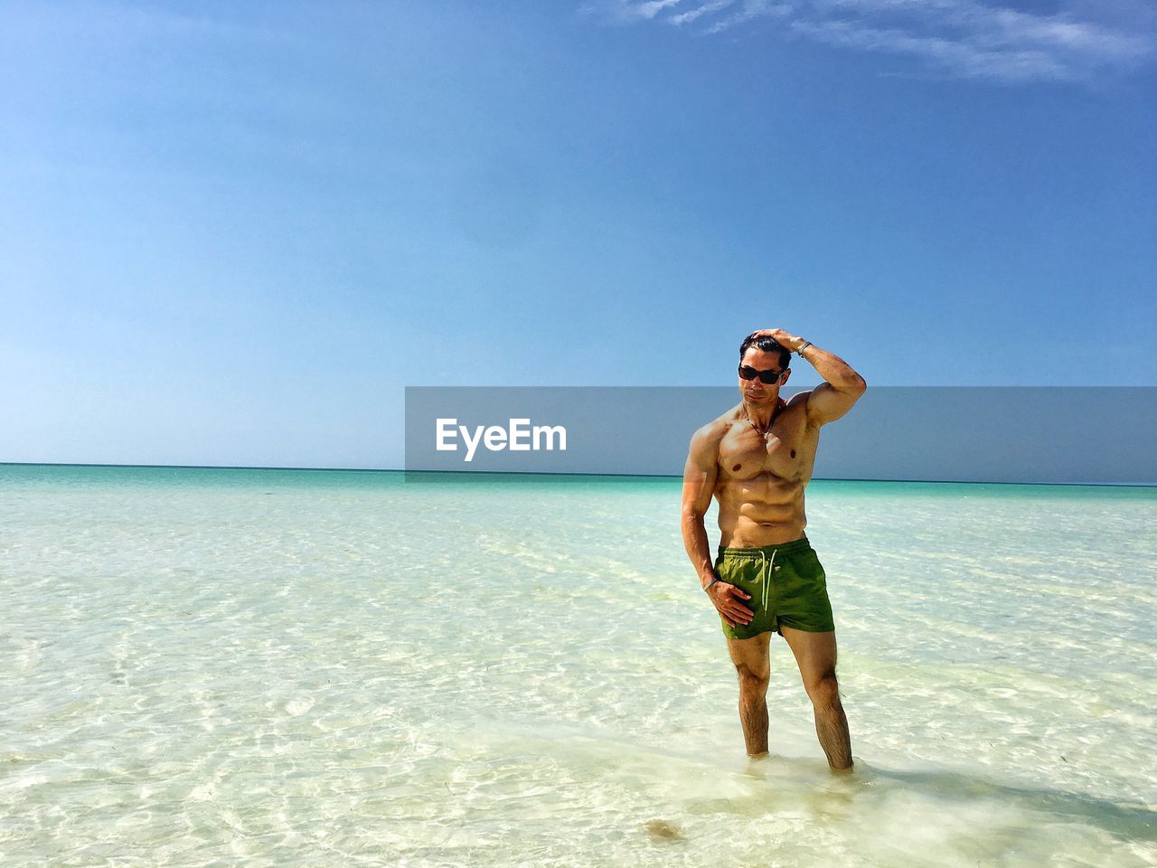 Shirtless man standing in sea on sunny day