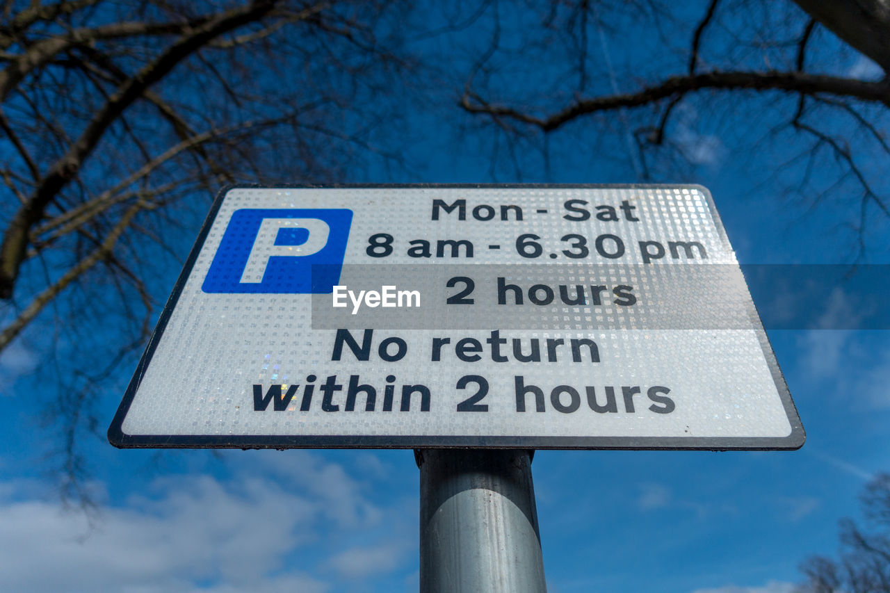 Low angle view of signboard against blue sky