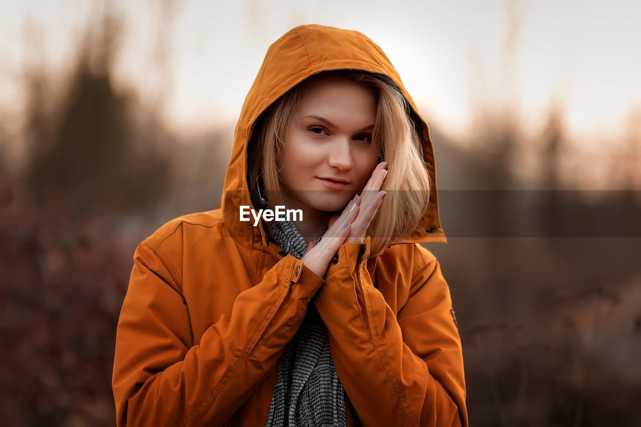 portrait of young woman wearing hat standing against trees