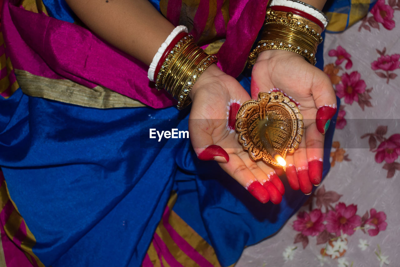 Hands of an indian woman holding diya or pradip on diwali .