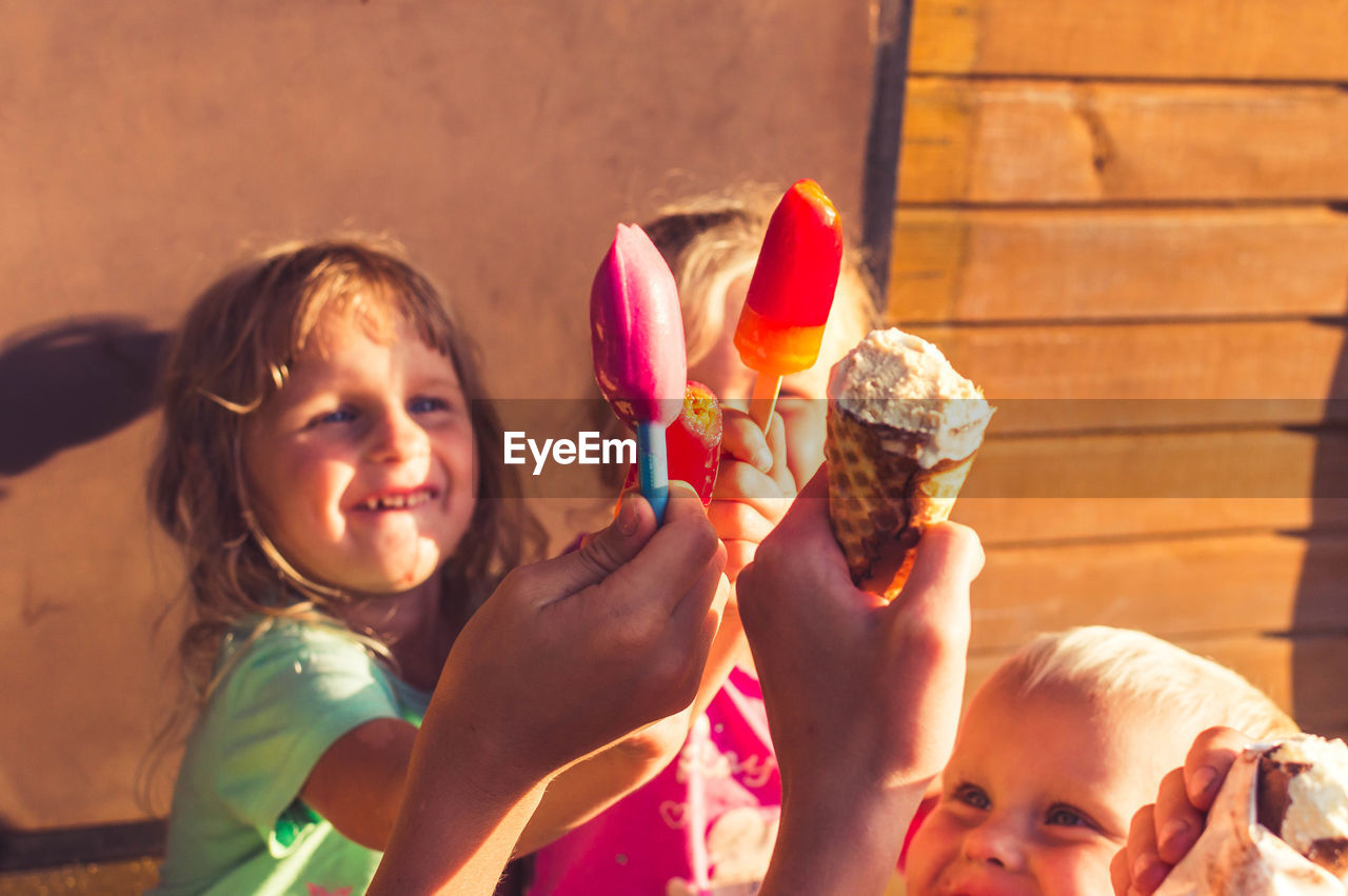 Close-up of smiling siblings toasting ice creams