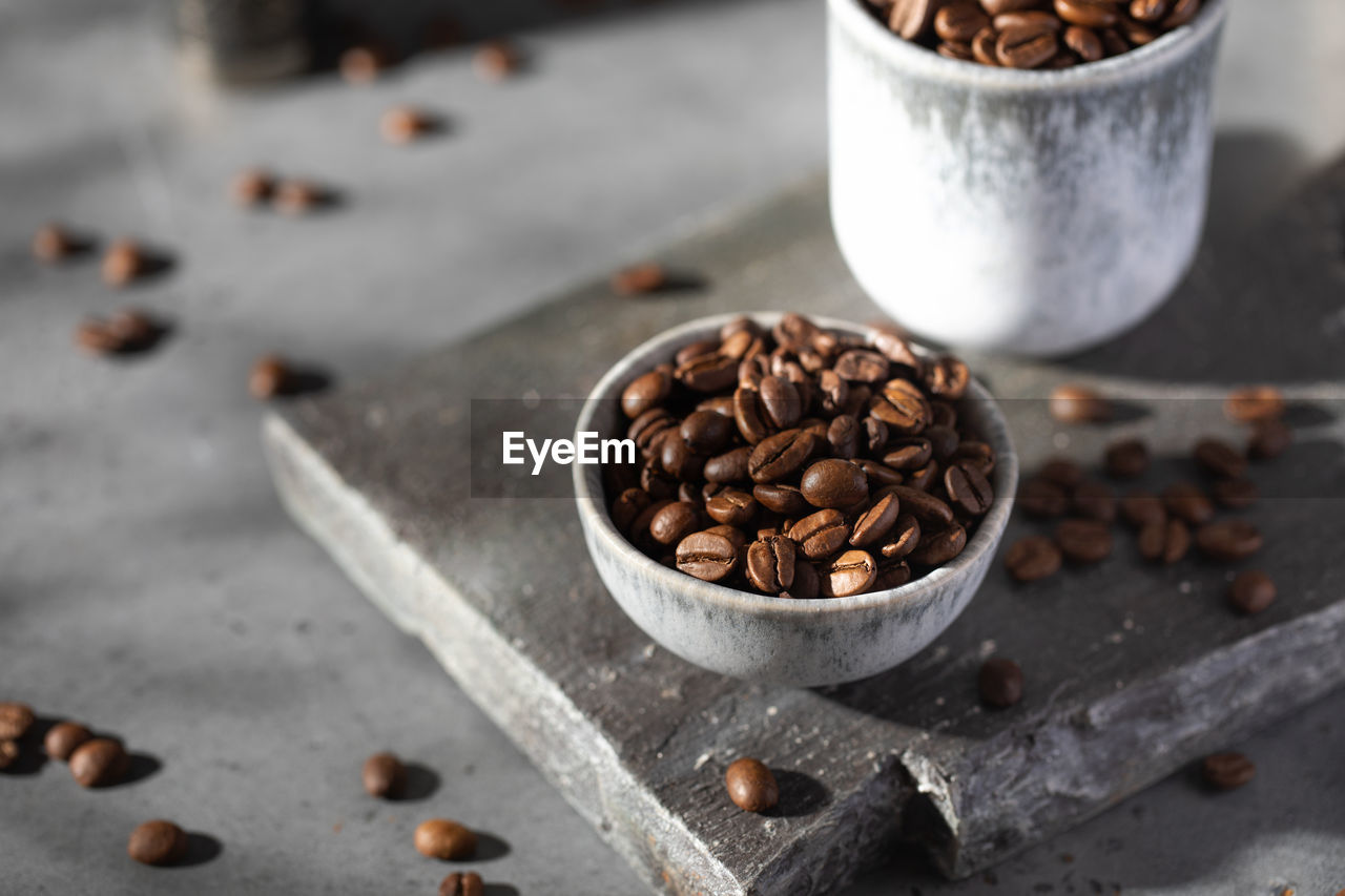 Roasted coffee beans in a bowl on a gray board.