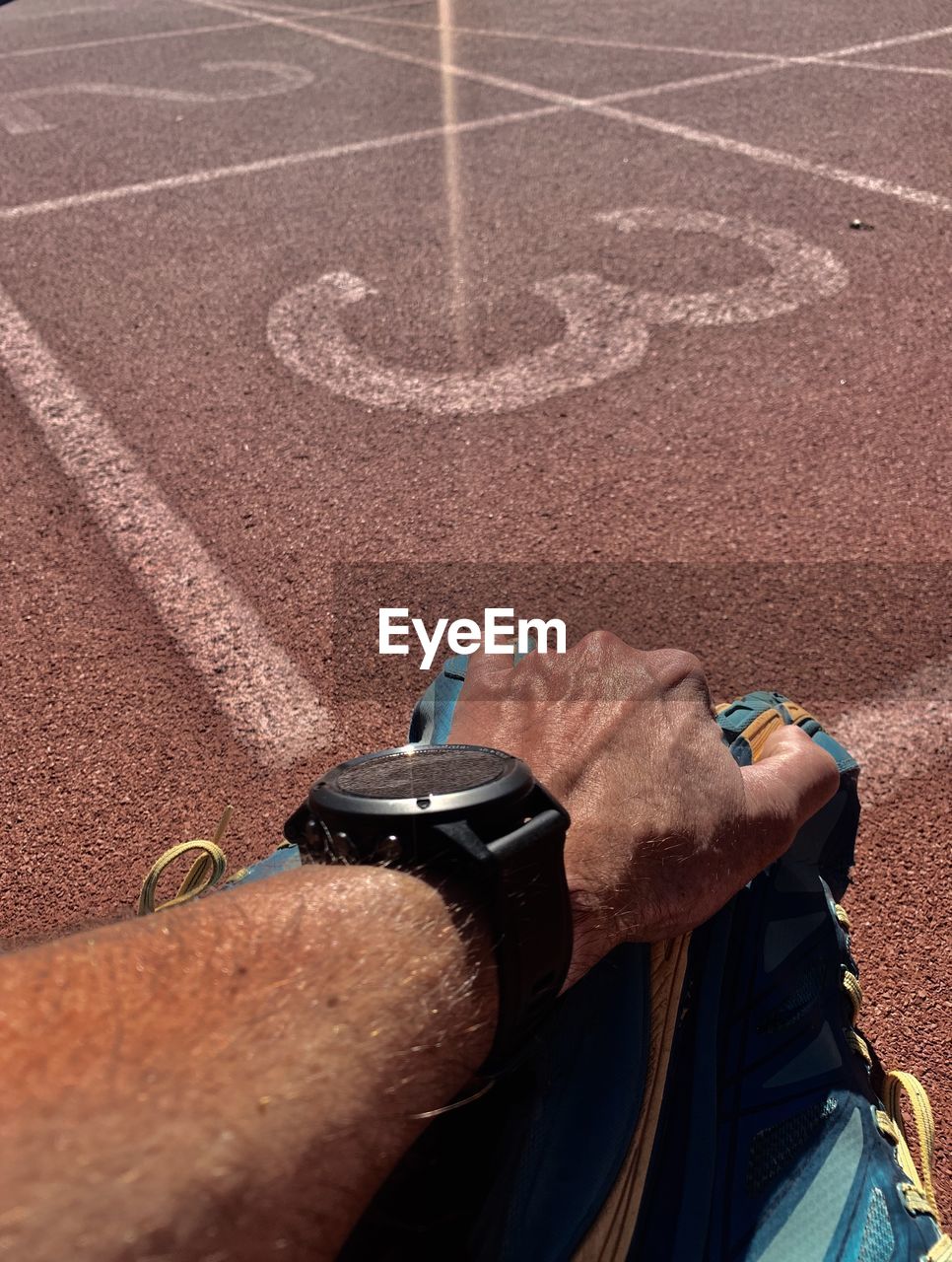 Midsection of man sitting by running track