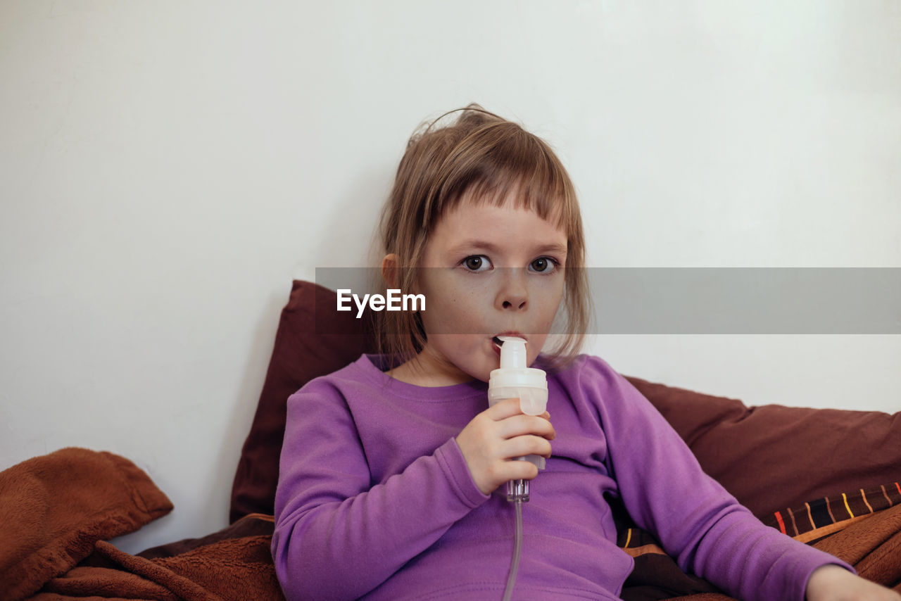 Sick child lies in bed and makes inhalation using a nebulizer.. treatment of cough with inhalation