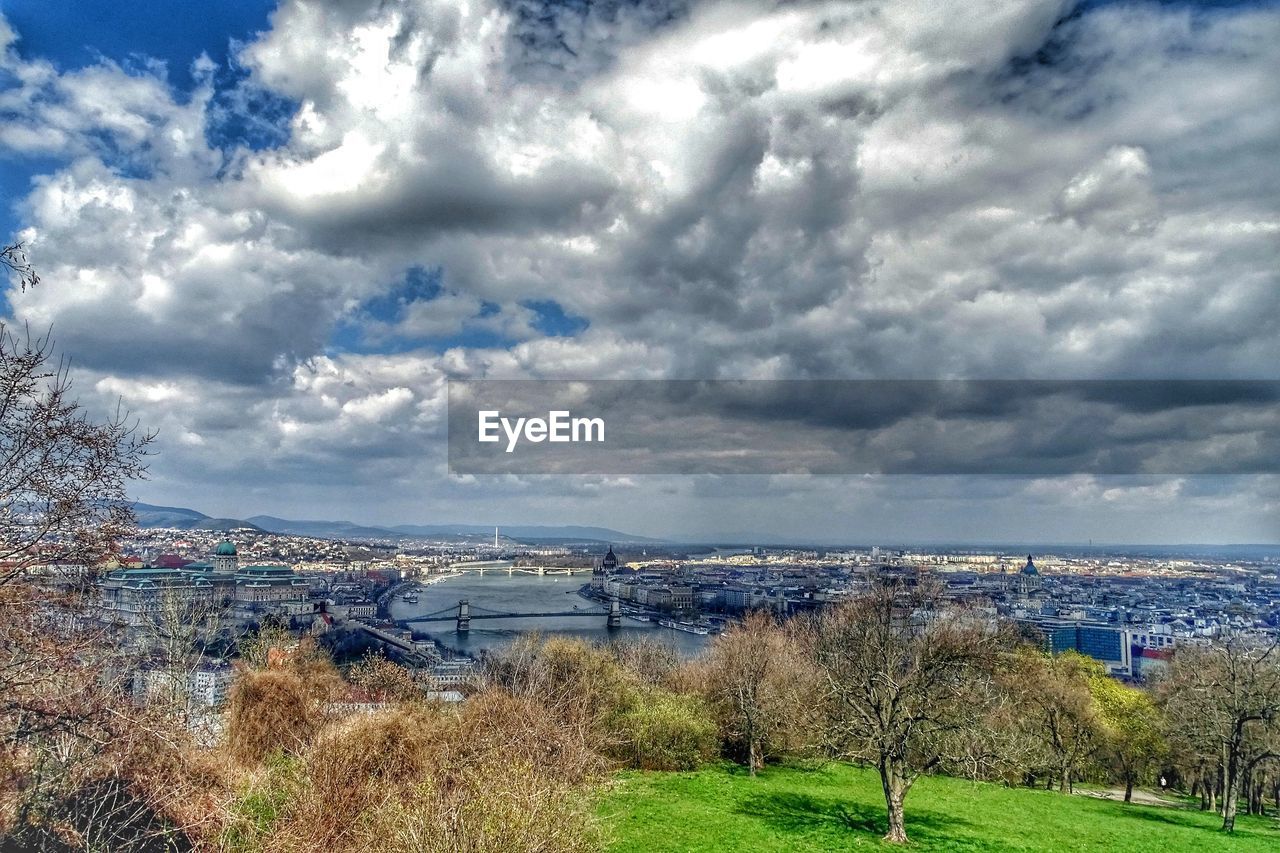 Scenic view of river in city against cloudy sky