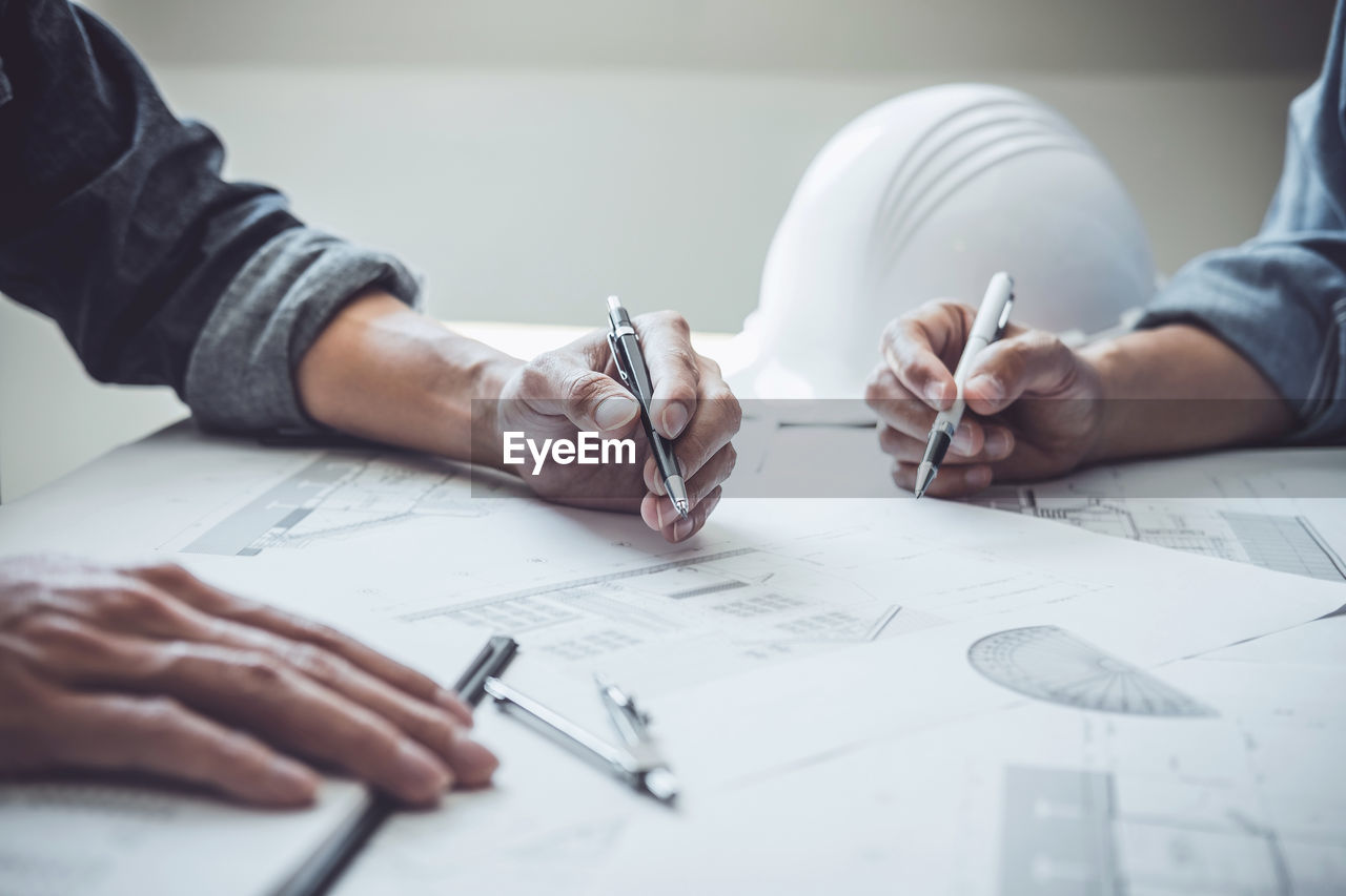 MIDSECTION OF MAN WORKING ON TABLE WITH PAPER