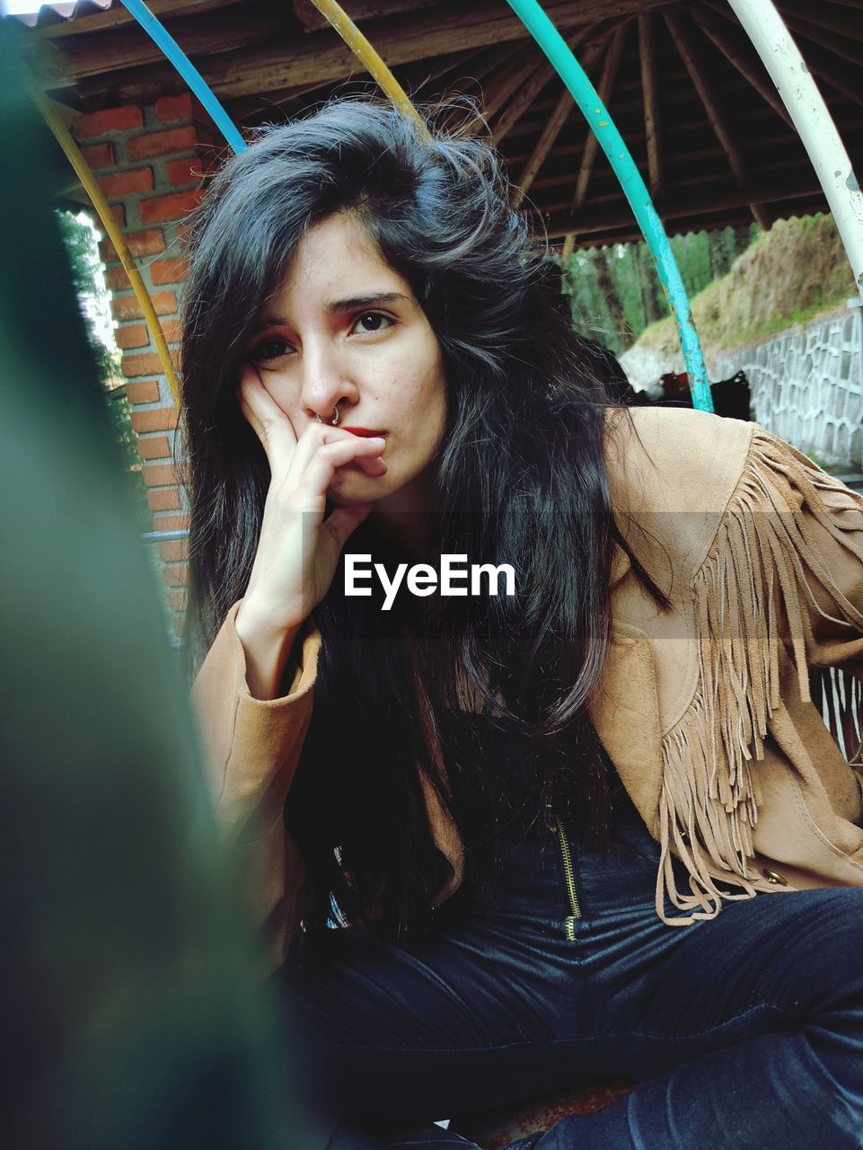 Portrait of young woman sitting outdoors thinking