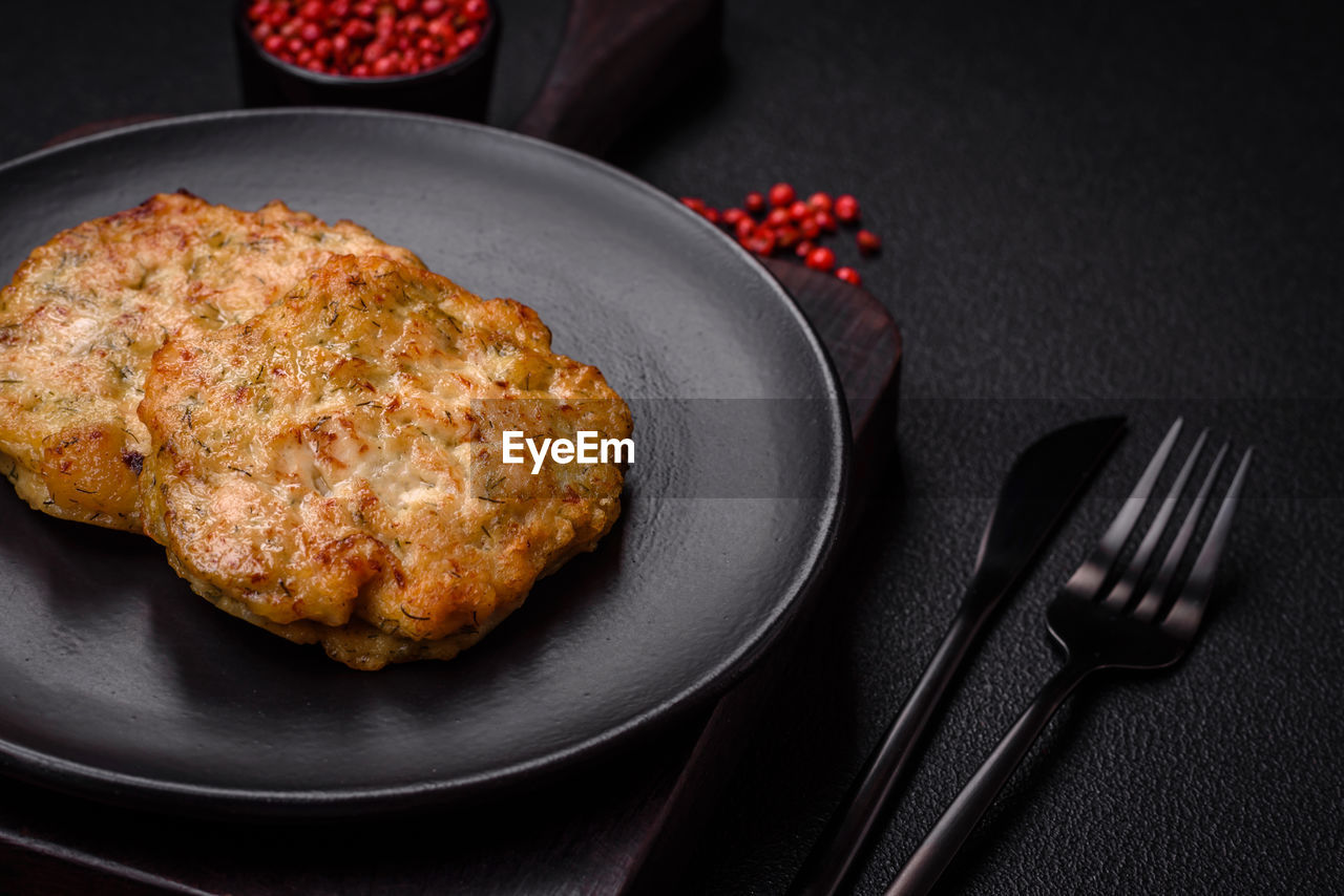food and drink, food, dish, fork, kitchen utensil, fried food, meat, healthy eating, studio shot, freshness, eating utensil, fast food, no people, meal, produce, plate, indoors, fruit, household equipment, black background, wellbeing, dinner, dark, fritter