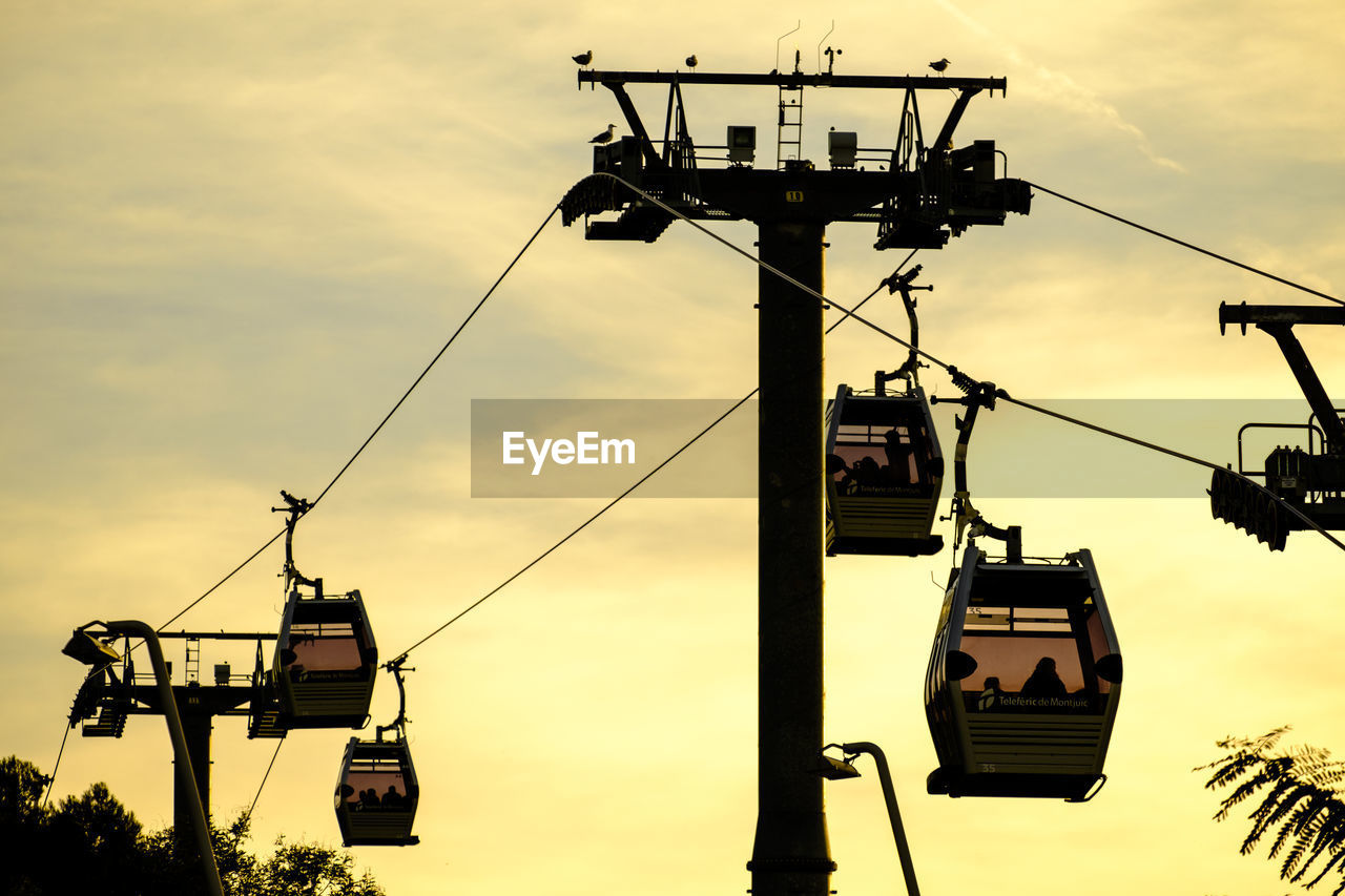 Low angle view of overhead cable cars against cloudy sky