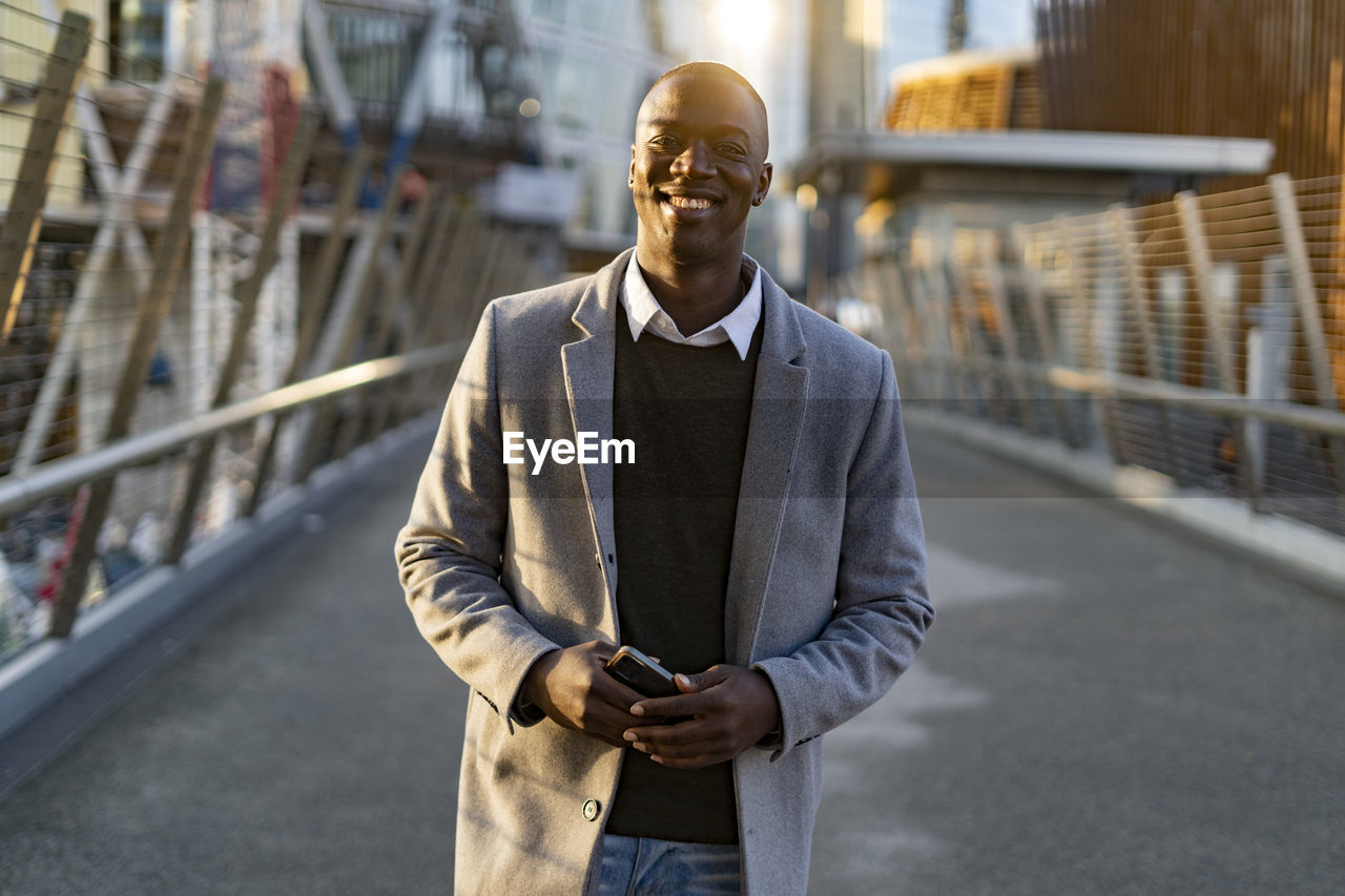 Businessman holding smart phone standing on bridge