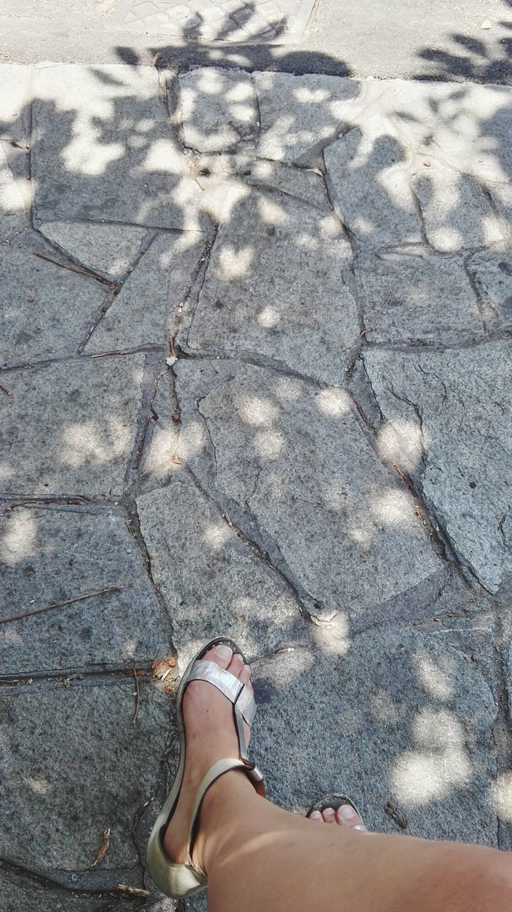 LOW SECTION OF WOMAN STANDING ON ASPHALT