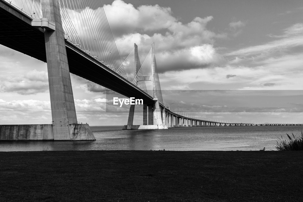 Low angle view of vasco da gama bridge against cloudy sky