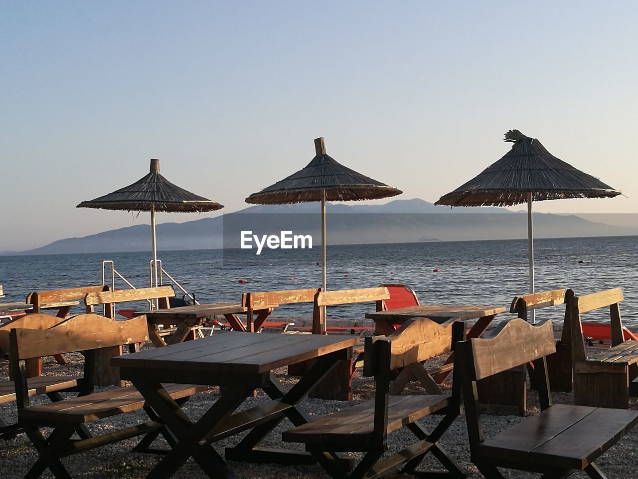 Chairs and tables at beach against sky