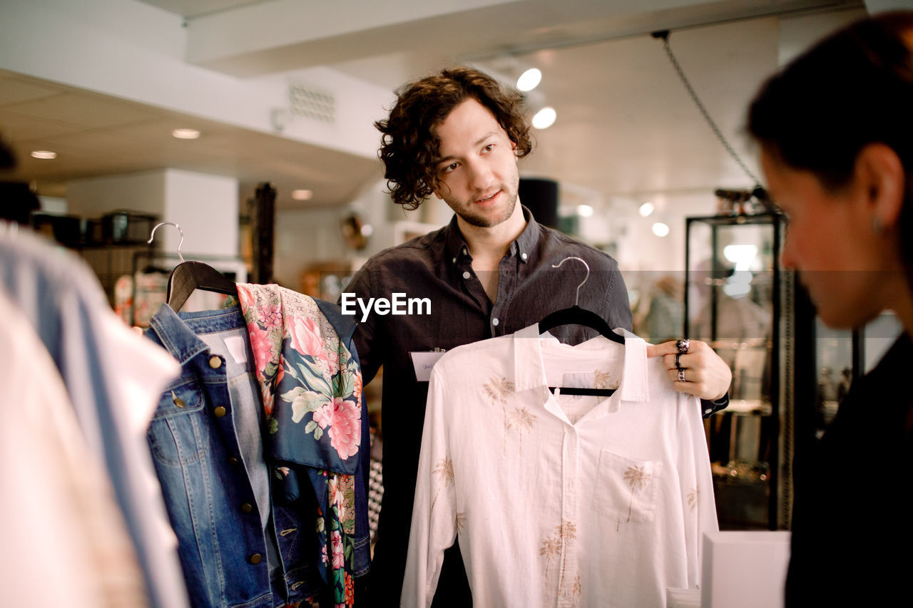 Salesman showing clothes to customer at store