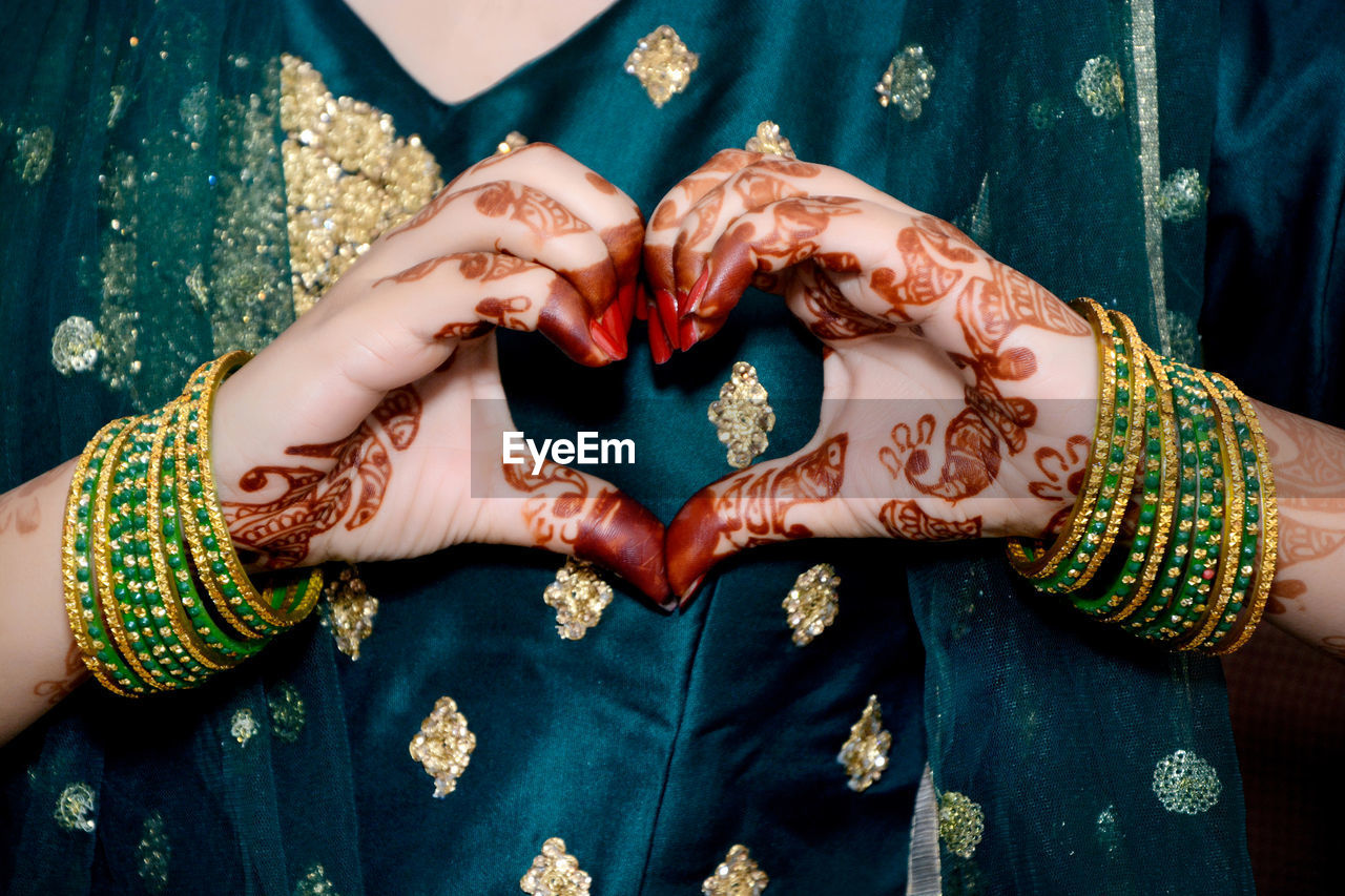 An indian bride making heart shape by her hands.