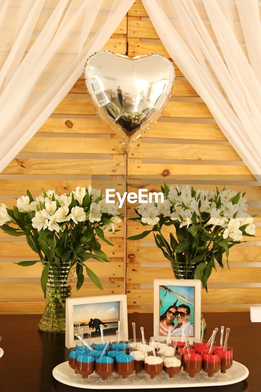 FLOWER VASE ON TABLE AGAINST ILLUMINATED WALL