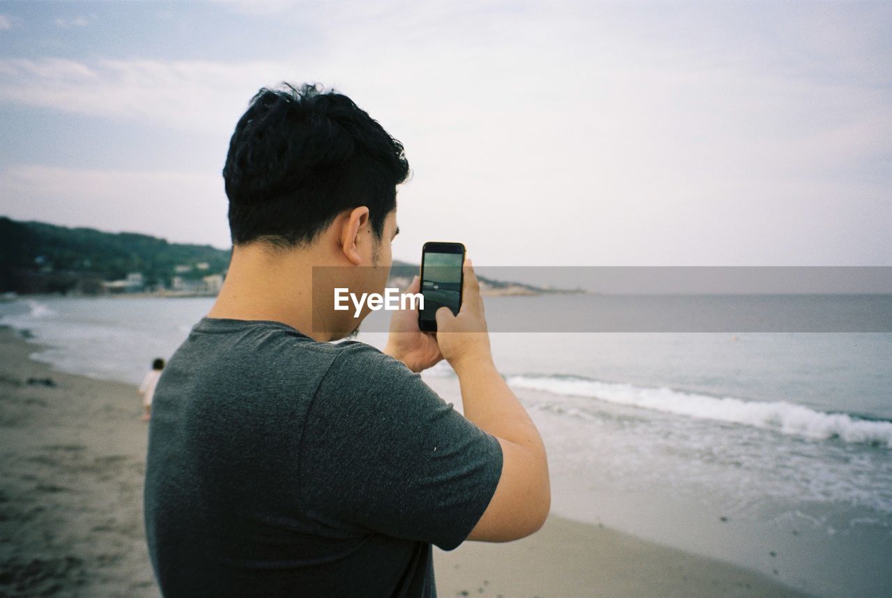 SIDE VIEW OF A YOUNG WOMAN TAKING SELFIE