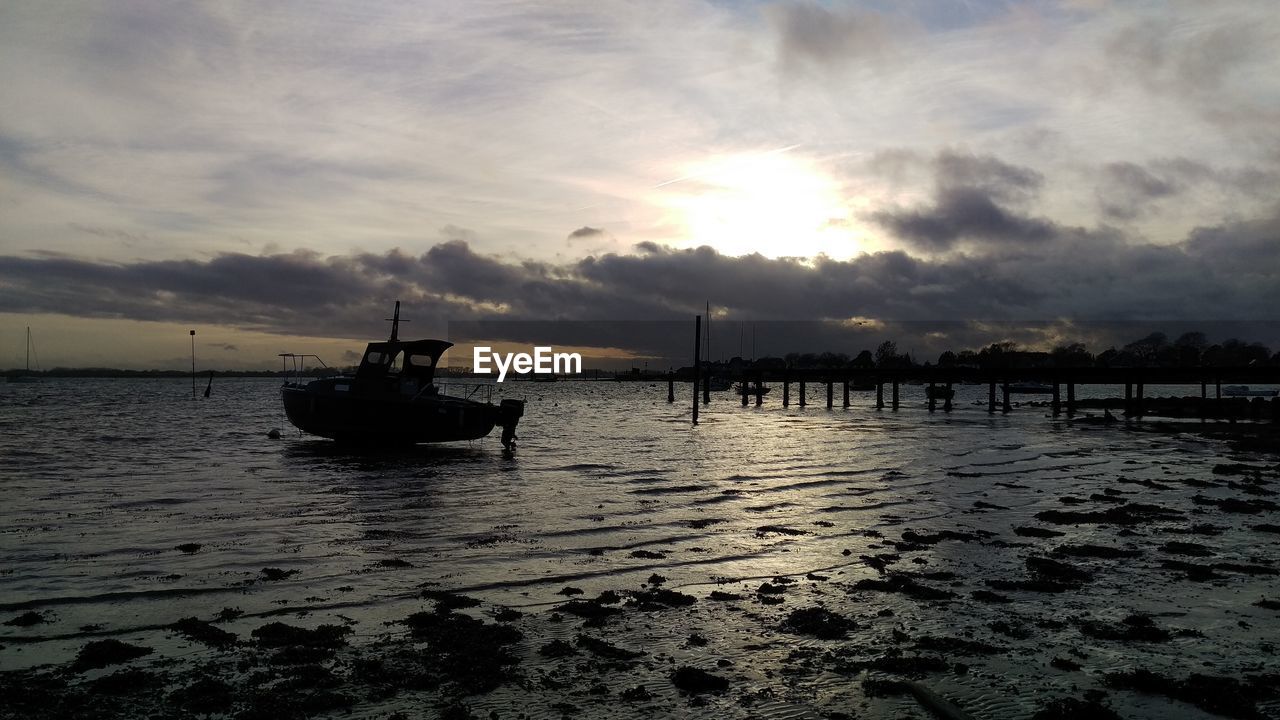 Scenic view of boat on sea against cloudy sky during sunset