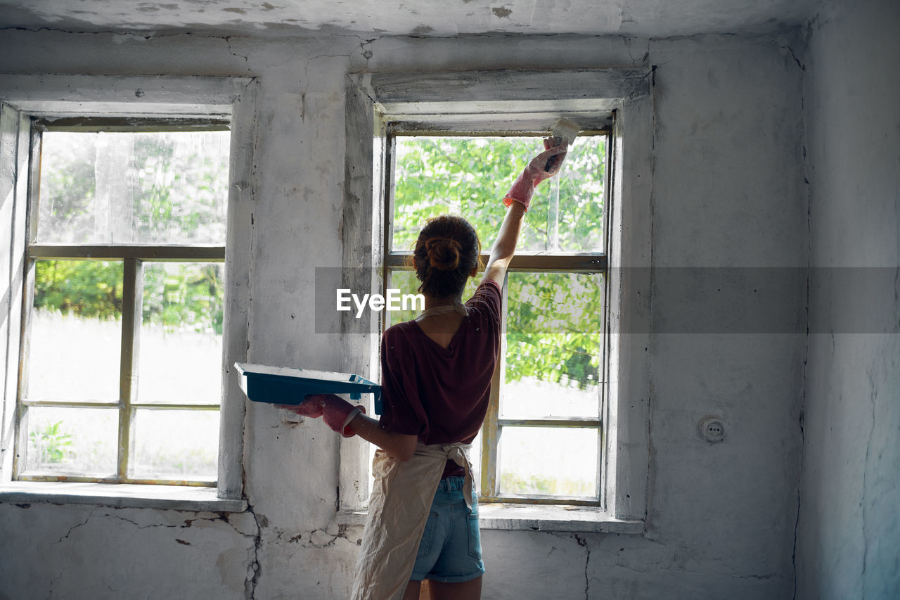 Rear view of woman standing by window