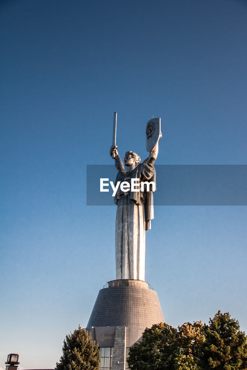 sky, sculpture, statue, architecture, clear sky, landmark, blue, nature, monument, human representation, no people, low angle view, plant, tree, travel destinations, day, memorial, built structure, history, sunny, the past, representation, travel, copy space, outdoors, craft