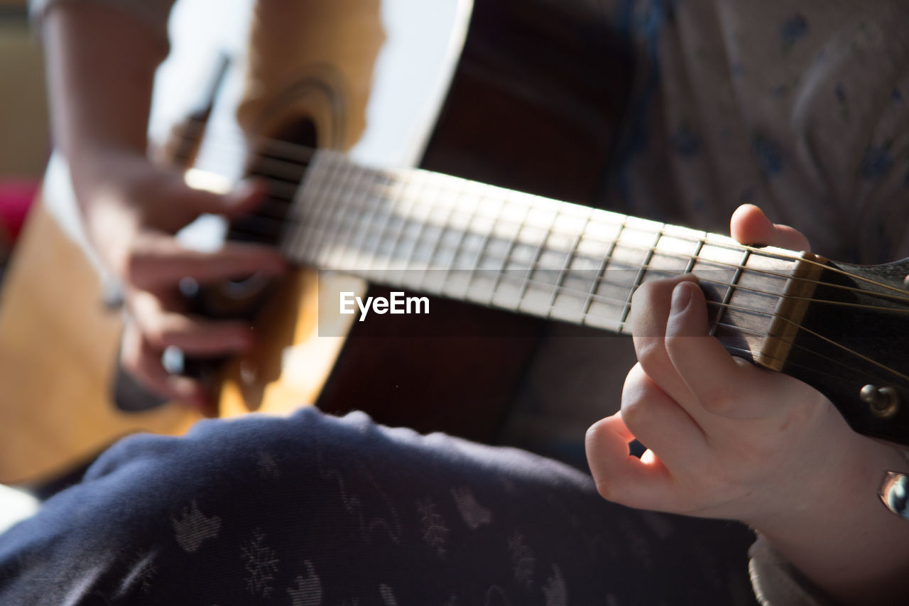 MIDSECTION OF MAN PLAYING GUITAR IN MUSIC CONCERT