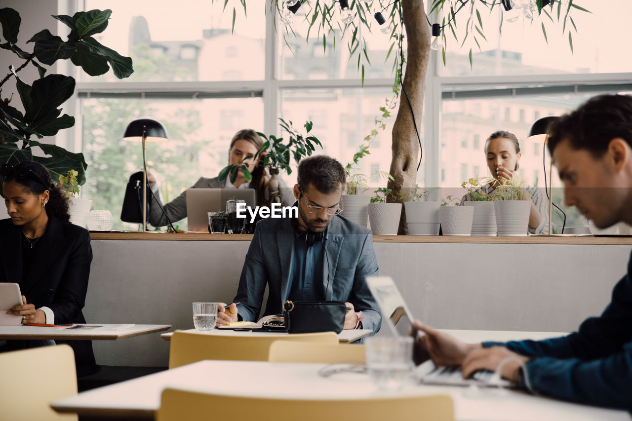 Male and female employees working at desk in coworking space