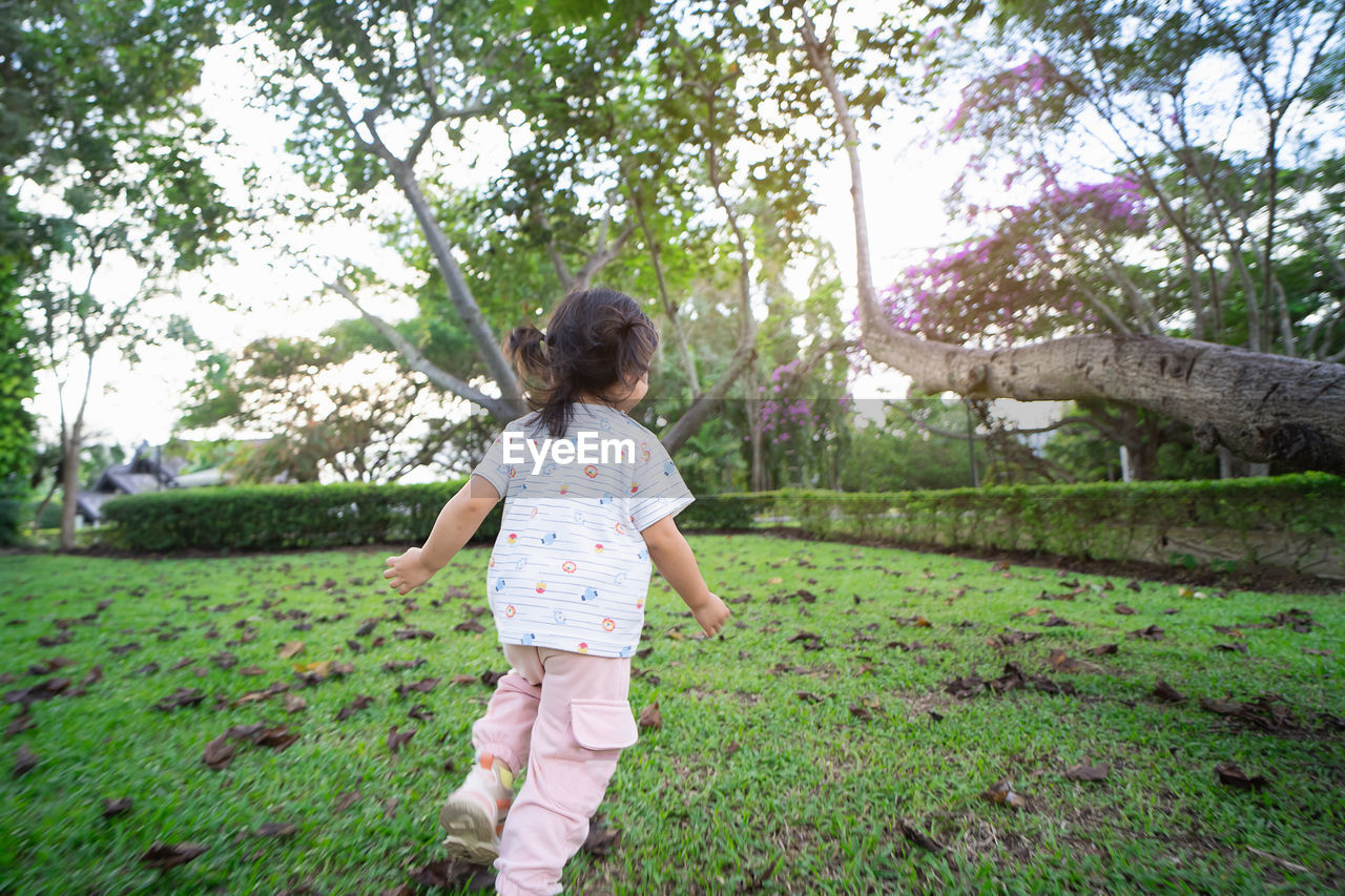 FULL LENGTH REAR VIEW OF GIRL STANDING ON GRASS