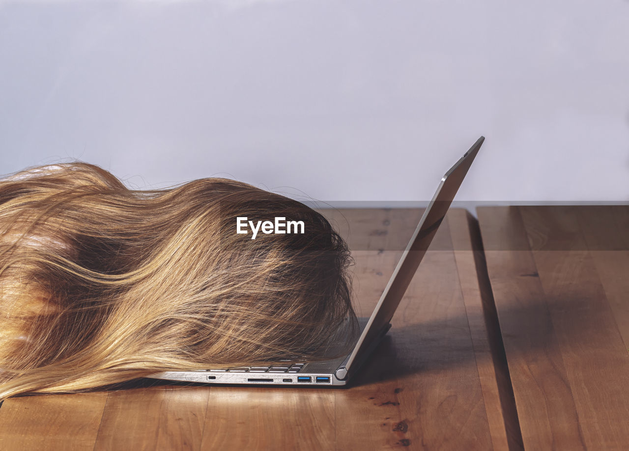 Woman resting on laptop against wall