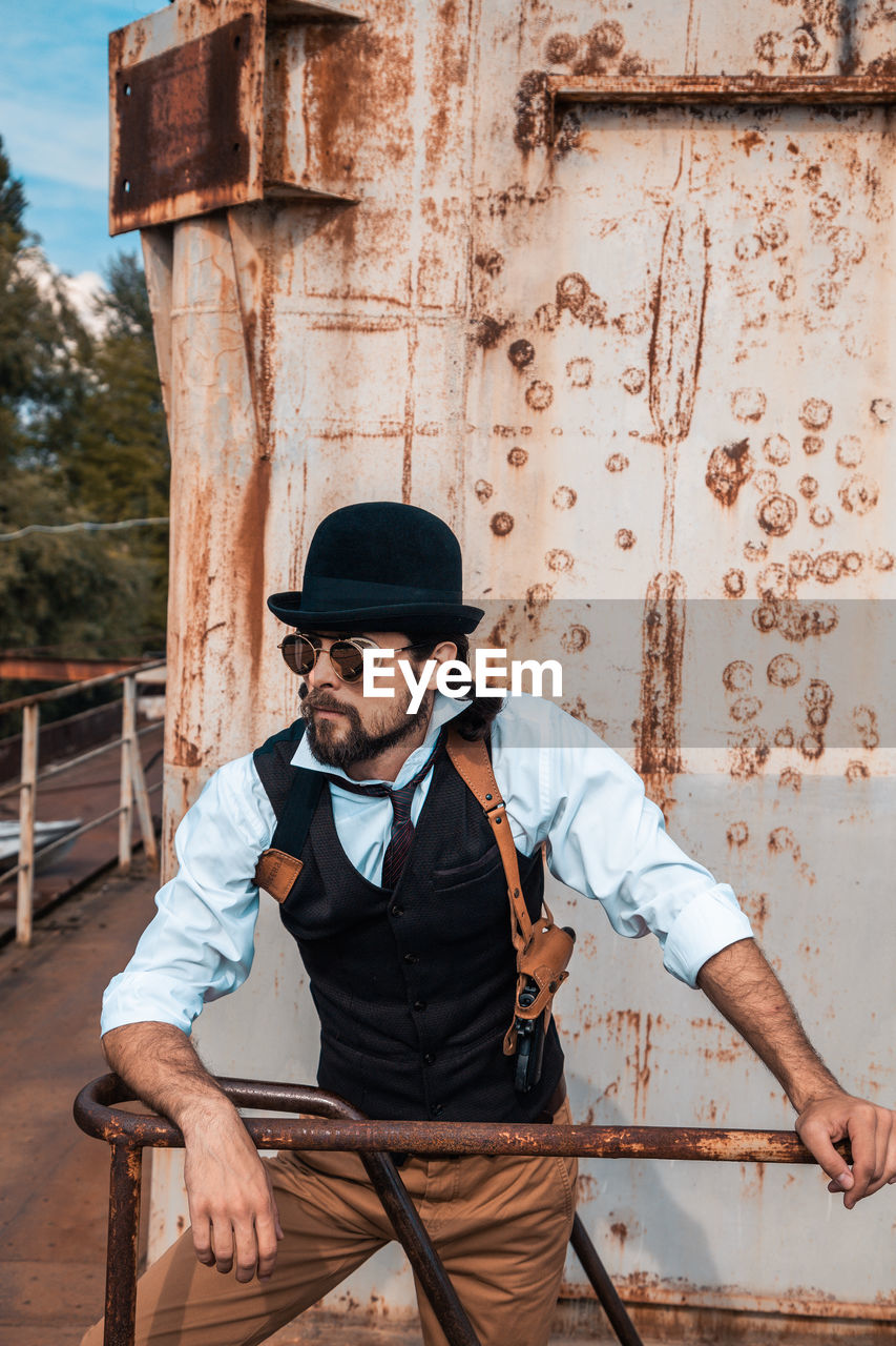 Full length of man wearing hat standing against wall