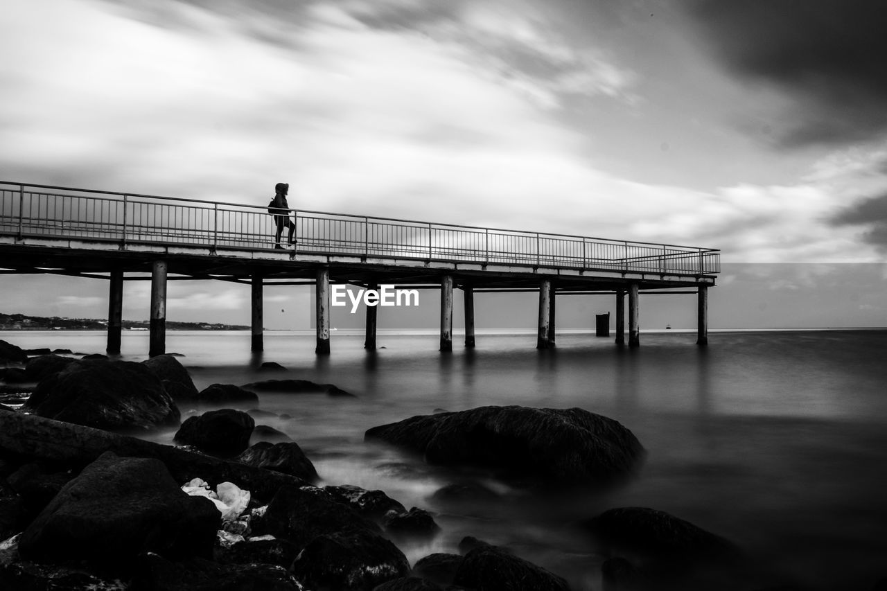 People standing on bridge over sea against sky