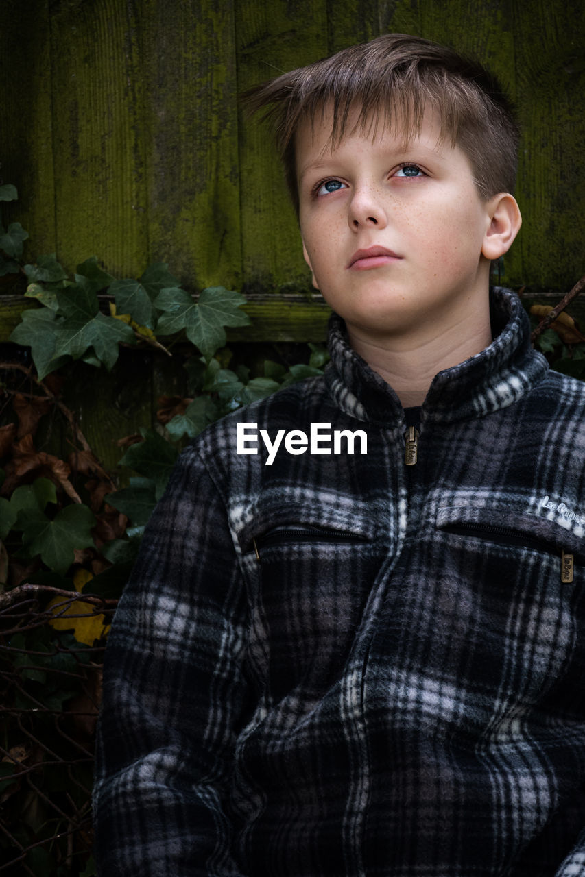 Portrait of boy standing against plants