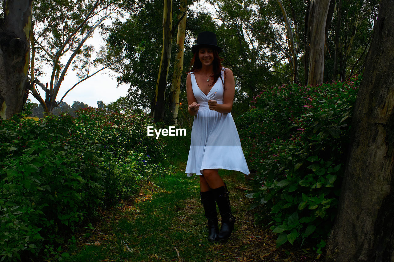 Full length portrait of woman standing against plants