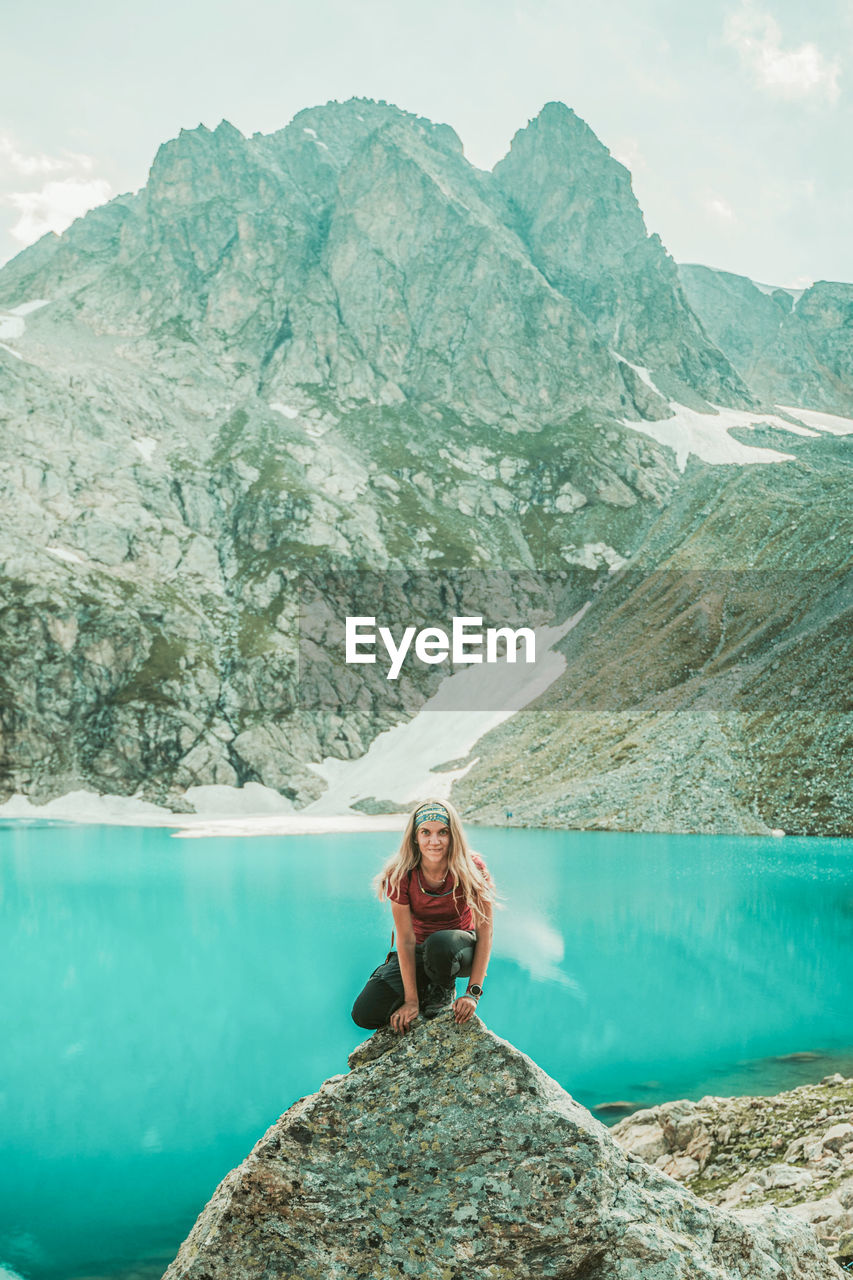 Woman sitting on rock by mountain