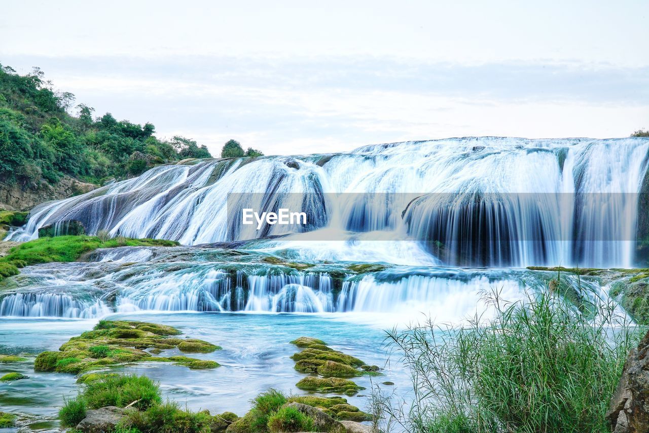 Scenic view of waterfall against sky