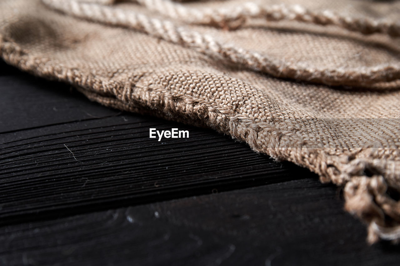 Twine and burlap on a black wooden background, still life