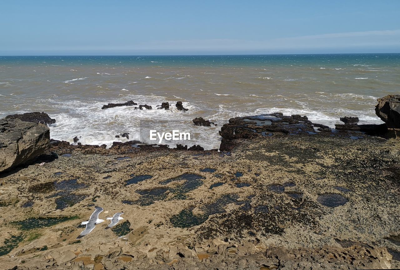 ROCKS ON BEACH AGAINST SKY